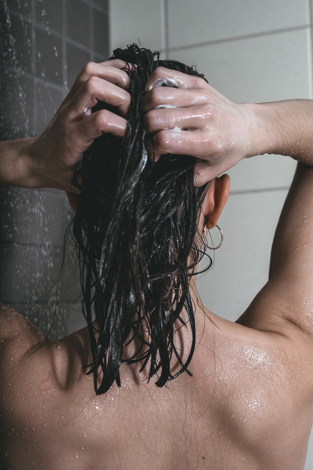 kobieta pod prysznicem nakłada maskę na włosy